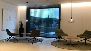 A modern living room with a large window, a painting, and a potted plant. - Hotel Las Terrazas (Burgos)