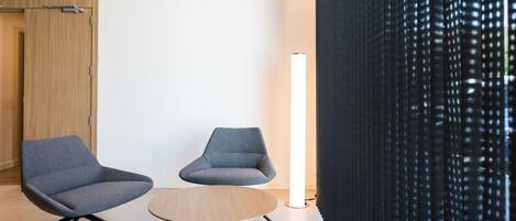 Una habitación moderna con dos sillones grises y una mesa redonda de madera.