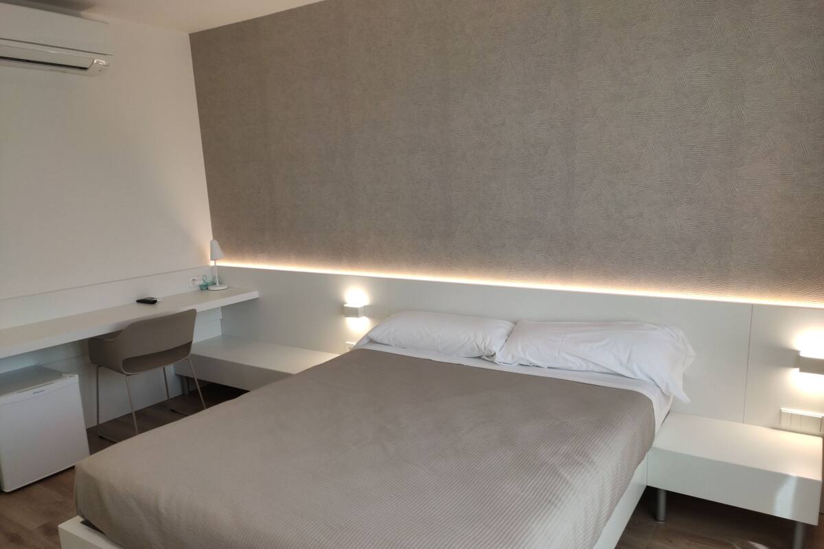 Quarto de hotel moderno com uma cama grande, uma escrivaninha e uma cadeira.