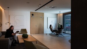 A modern interior with a sofa, a table, and two chairs. There is a wooden door and a window with blinds. - Hotel Las Terrazas (Burgos)