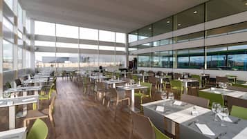Ein großzügiges Restaurant mit hohen Decken, großen Fenstern und modernem Interieur.