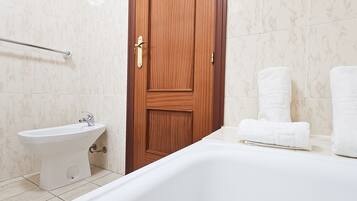Un baño con puerta de madera, un lavabo blanco y dos toallas blancas sobre el mostrador.
