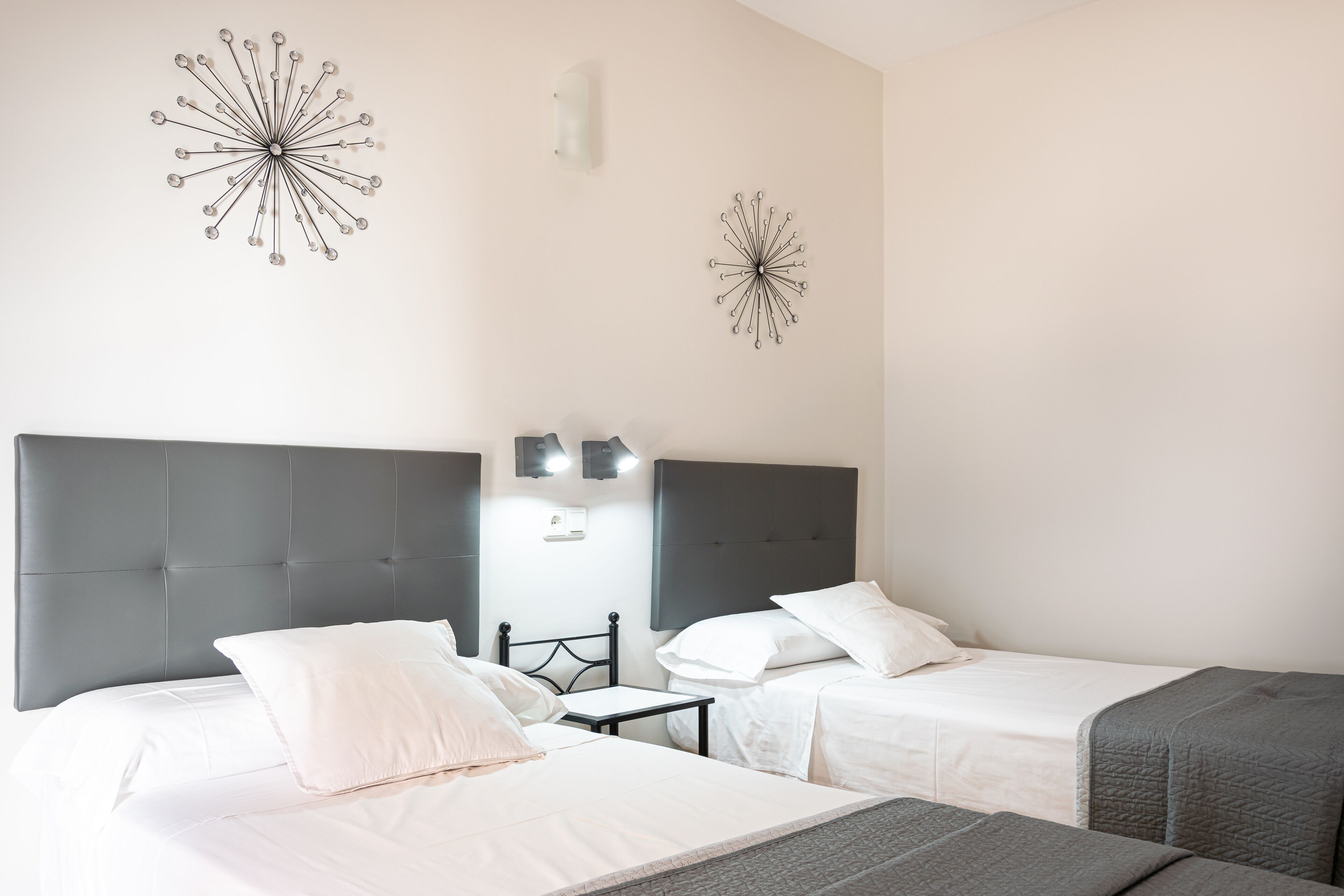 Une chambre d’hôtel avec deux lits, une petite table et des œuvres d’art décoratives au mur.