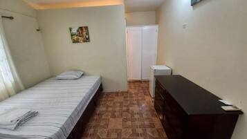 A small, clean room with a bed, a dresser, and a wardrobe.