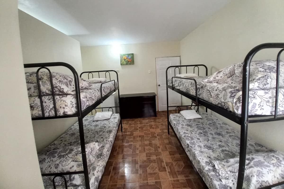 Un dormitorio con literas, suelo de baldosas, una puerta y un cuadro en la pared.