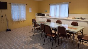 Un comedor con mesa y sillas, microondas y ventana con cortinas.