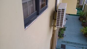 A residential building with a narrow staircase, outdoor air conditioning units, and potted plants.