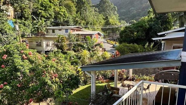 Zona residencial con vistas a una colina, un pequeño estanque y un balcón con mesa y sillas.
