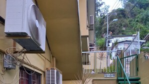 Un edificio con unidades de aire acondicionado, una escalera con barandales y plantas en macetas en el suelo.