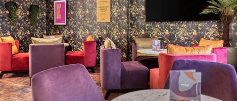 A room with a floral wallpaper, a flat-screen TV, and a table with a candle.
