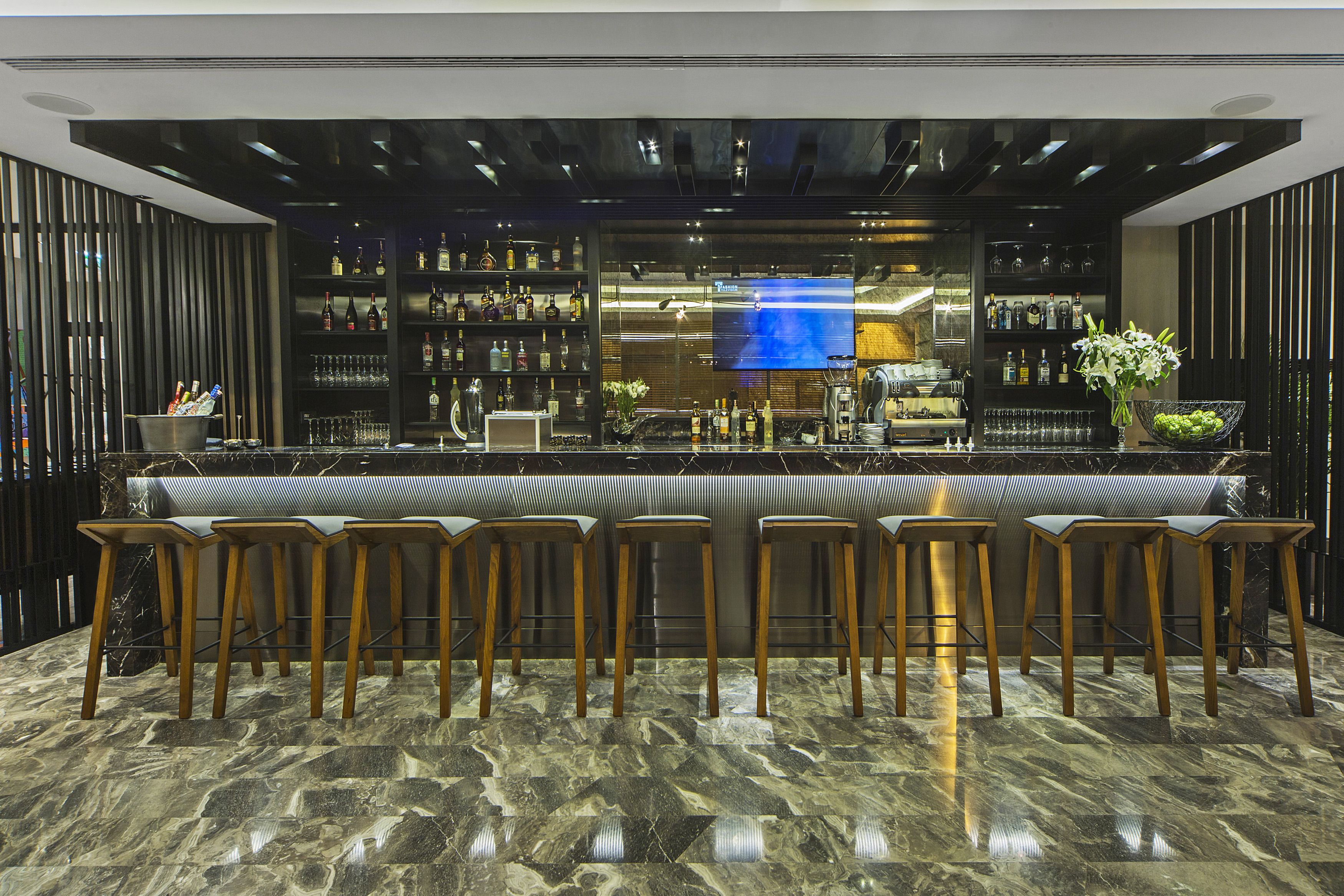 A bar area with a marble floor, wooden stools, and a bar counter.