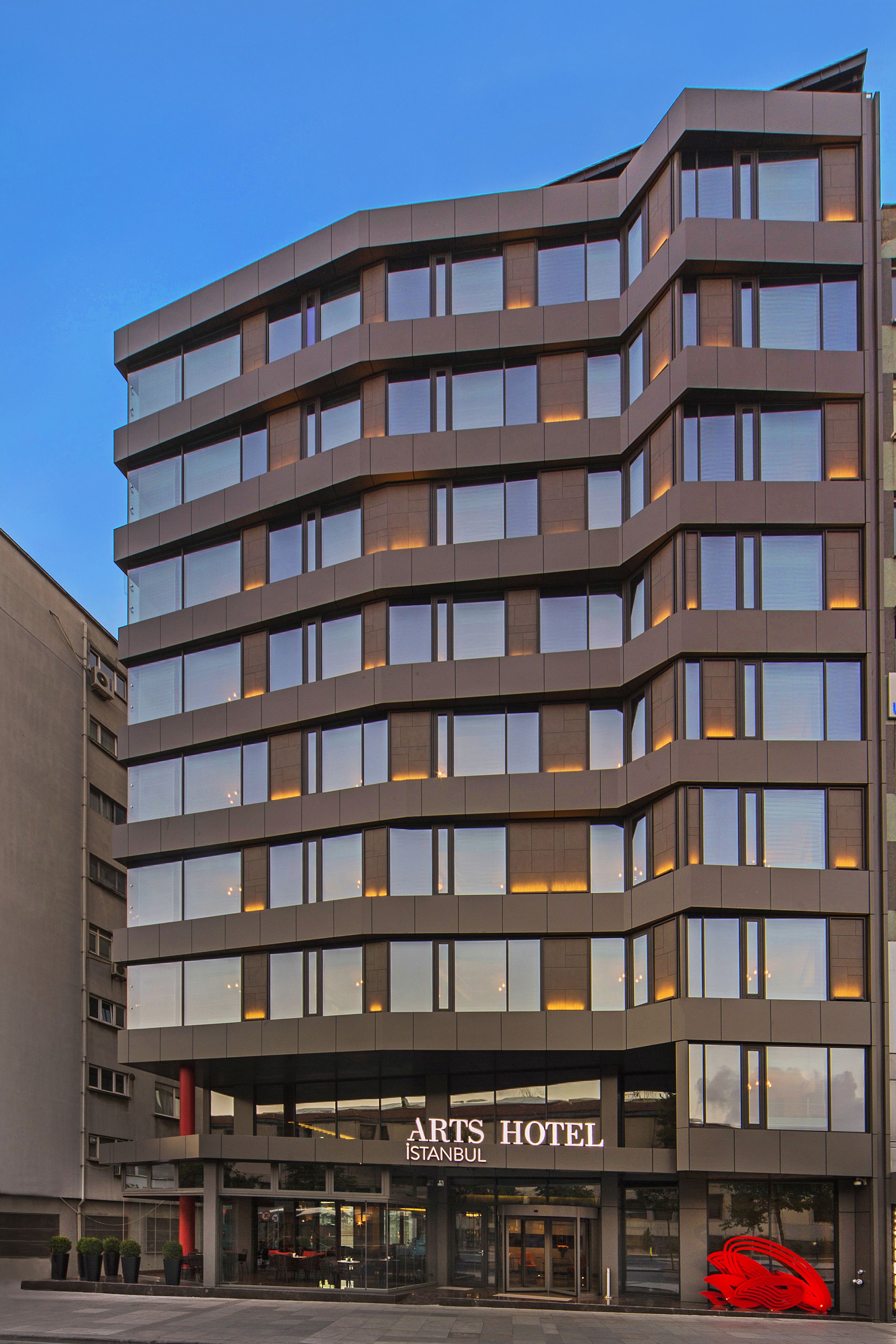 A modern building with multiple floors, large windows, and a sign reading "Arts Hotel Istanbul."