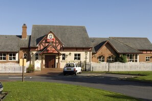 A building with a sign that reads 'TOBY CARVER,' a white picket fence, and a car parked in front. - Premier Inn Wolviston/Wynyard (Billingham)