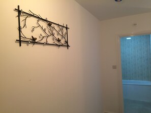 A wall-mounted art piece with branches and bird figures. - Canary Heights Apartments (London)