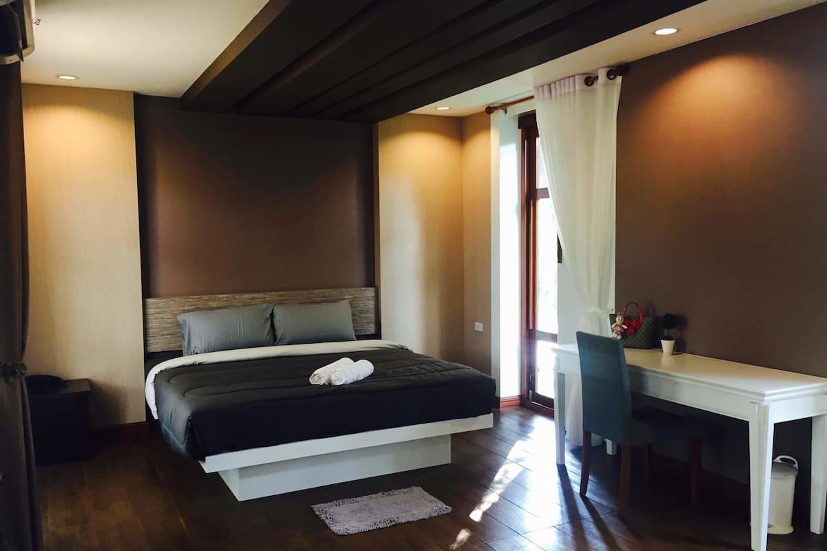 A bedroom with a bed, a desk, and a chair.