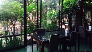Un restaurant doté de grandes fenêtres donnant sur un jardin luxuriant et des arbres.