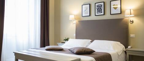 A neatly arranged hotel room with a large bed, bedside lamps, a bedside table, and a window with curtains.