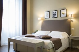 Camera d'albergo ben ordinata con un letto grande, abat-jour, comodino e finestra con tende.