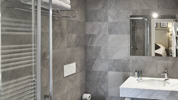 A modern bathroom with a glass shower enclosure, a bidet, a toilet, and a vanity with a mirror.