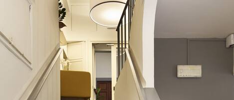 A staircase with a grey carpet and gold handrails, leading to a landing with a light fixture.