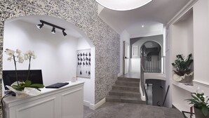Una moderna recepción con pared de piedra, una escalera y vistas a otra habitación.
