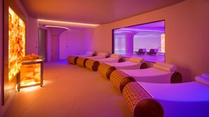 A modern spa room with massage tables, a reception area with a stone wall, and a large mirror reflecting the room. - Valle di Assisi Country Apartments (Assisi)