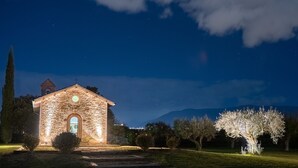 A stone church with a bell tower, surrounded by trees and a clear night sky. - Valle di Assisi Country Apartments (Assisi)