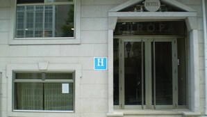 Entrada de un hotel con un cartel que dice 'EUROPA' y un letrero azul en forma de 'H' que indica un hotel.