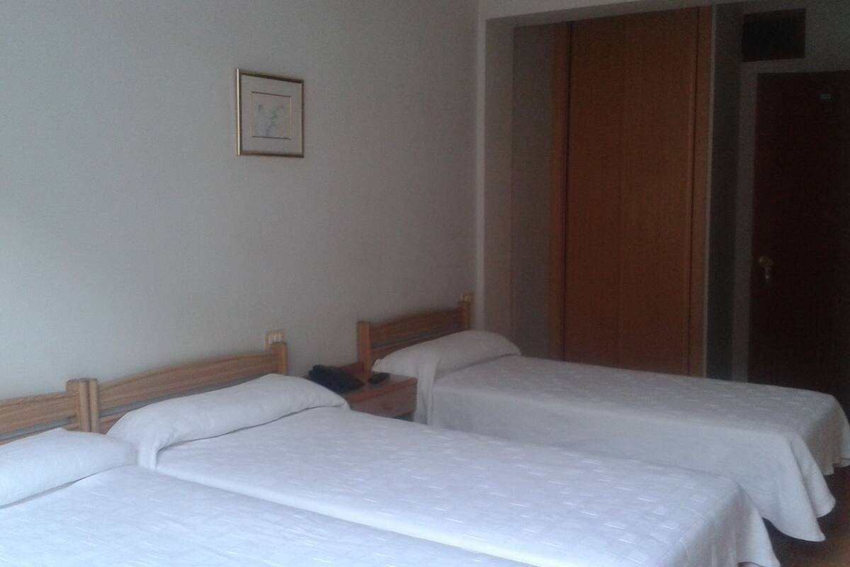 A room with two single beds, a wooden headboard, a small bedside table, and a framed picture on the wall.