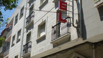 Un edificio de hotel con un llamativo letrero rojo, varios balcones y un cielo azul despejado.