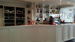 Zona de bar con estantes llenos de botellas y vasos.