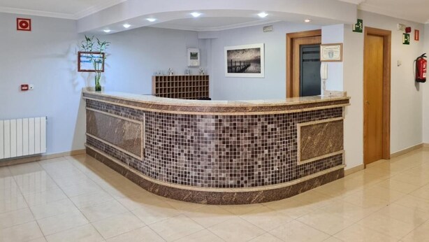 Un área de recepción con mostrador curvo, salpicadero de azulejos y puerta de madera.