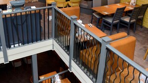 En restaurang med en vägg av tegelsten, träbord och bekväma sittplatser med kuddar.