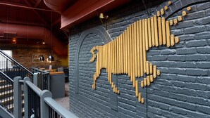 En trappa som leder upp till en sittgrupp med en tegelvägg och ett dekorativt, gyllene mönster.