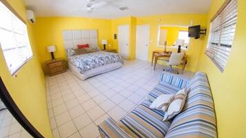 A bedroom with a bed, a sofa, a desk, and a television.