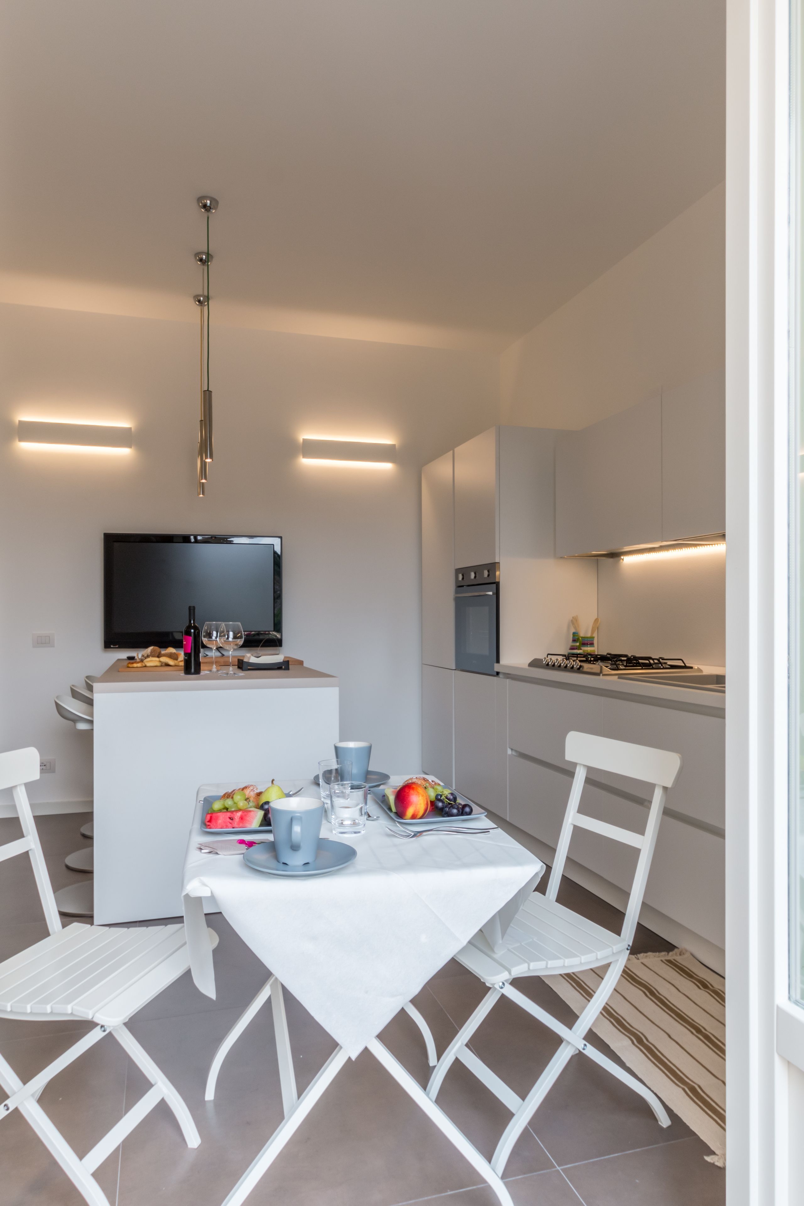 A modern kitchen with a dining area, a flat-screen TV, and a gas stove.