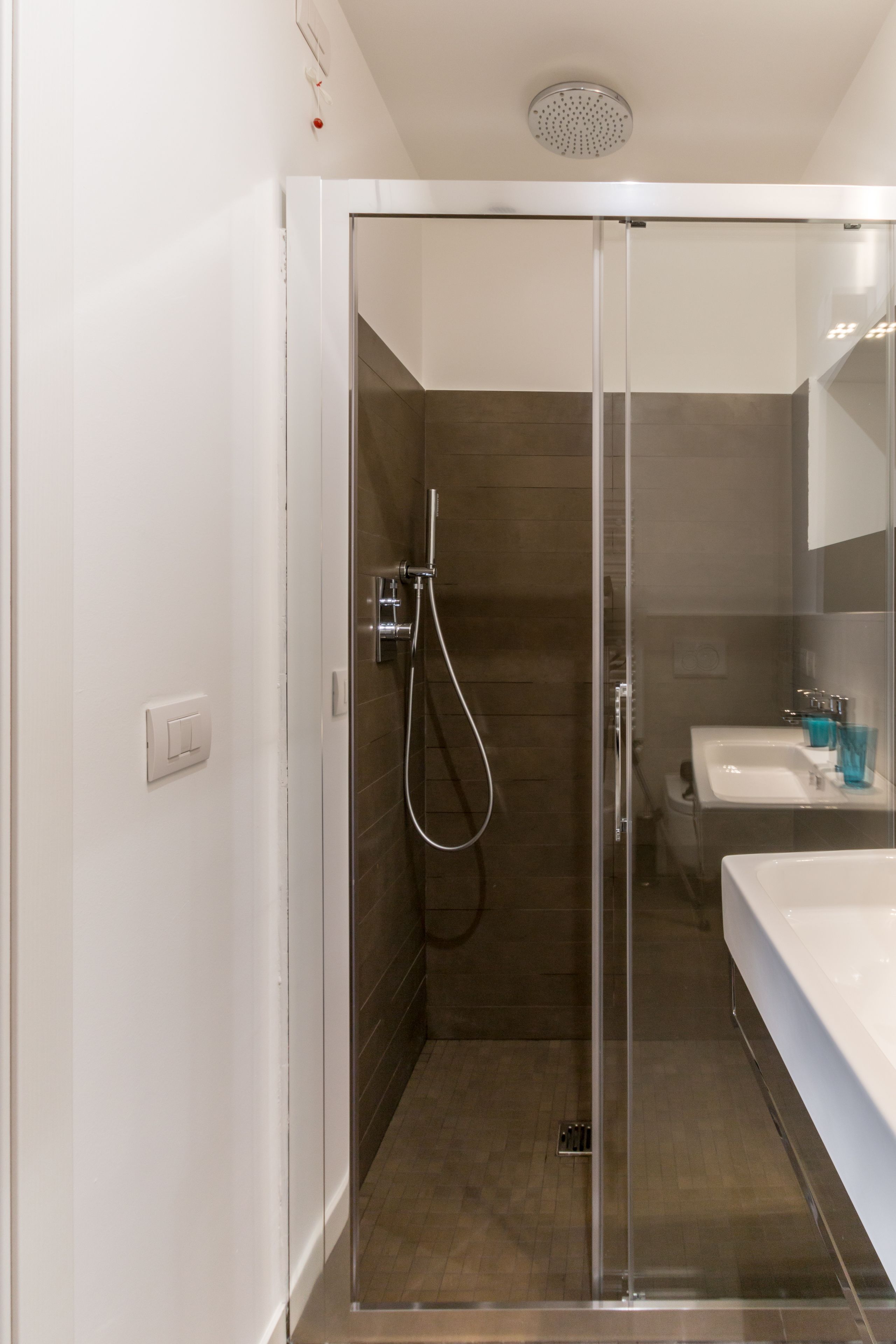 Une salle de bain moderne avec une douche à parois de verre, un lavabo blanc et un miroir au-dessus du lavabo.