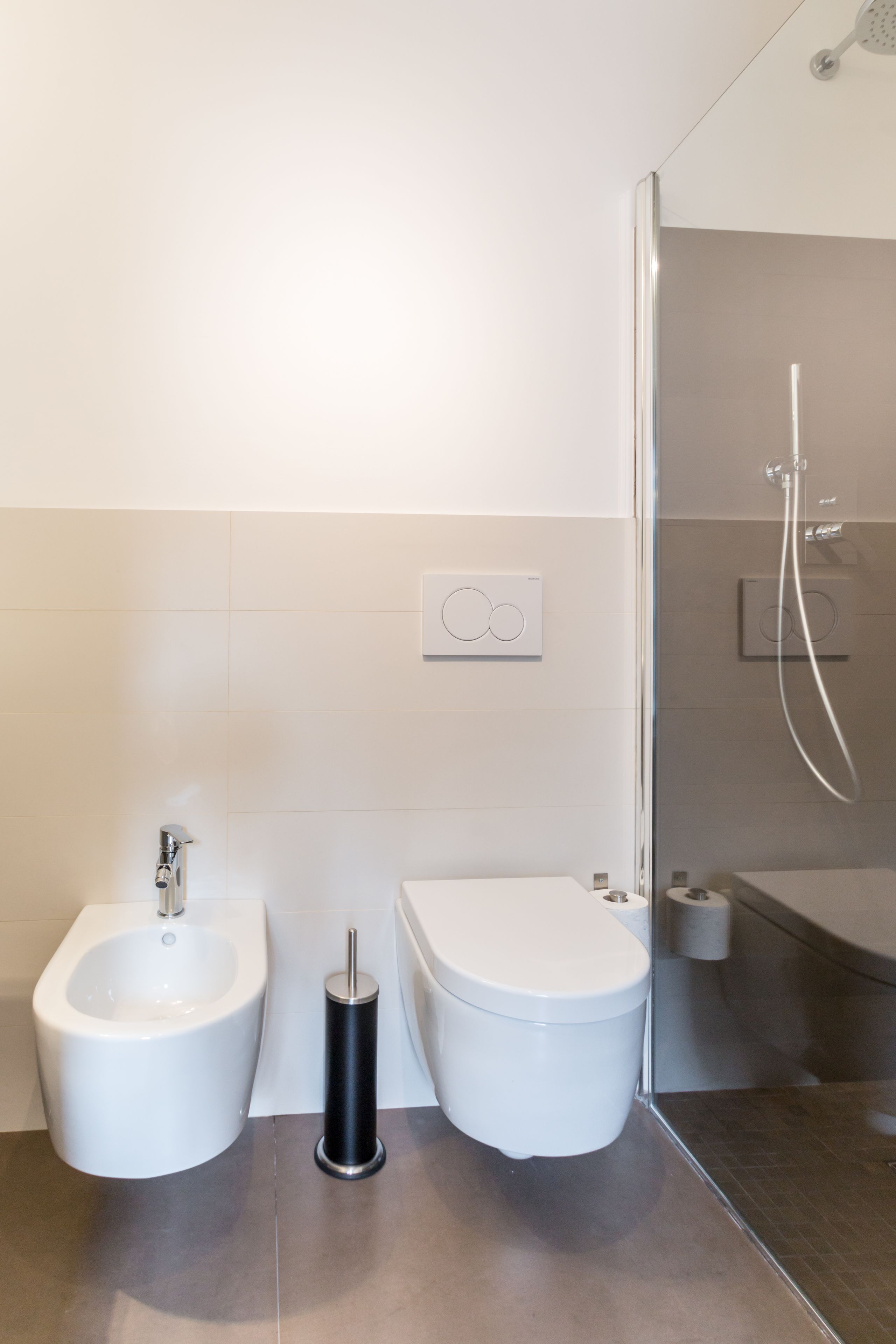 A modern bathroom with a bidet, toilet, and shower.