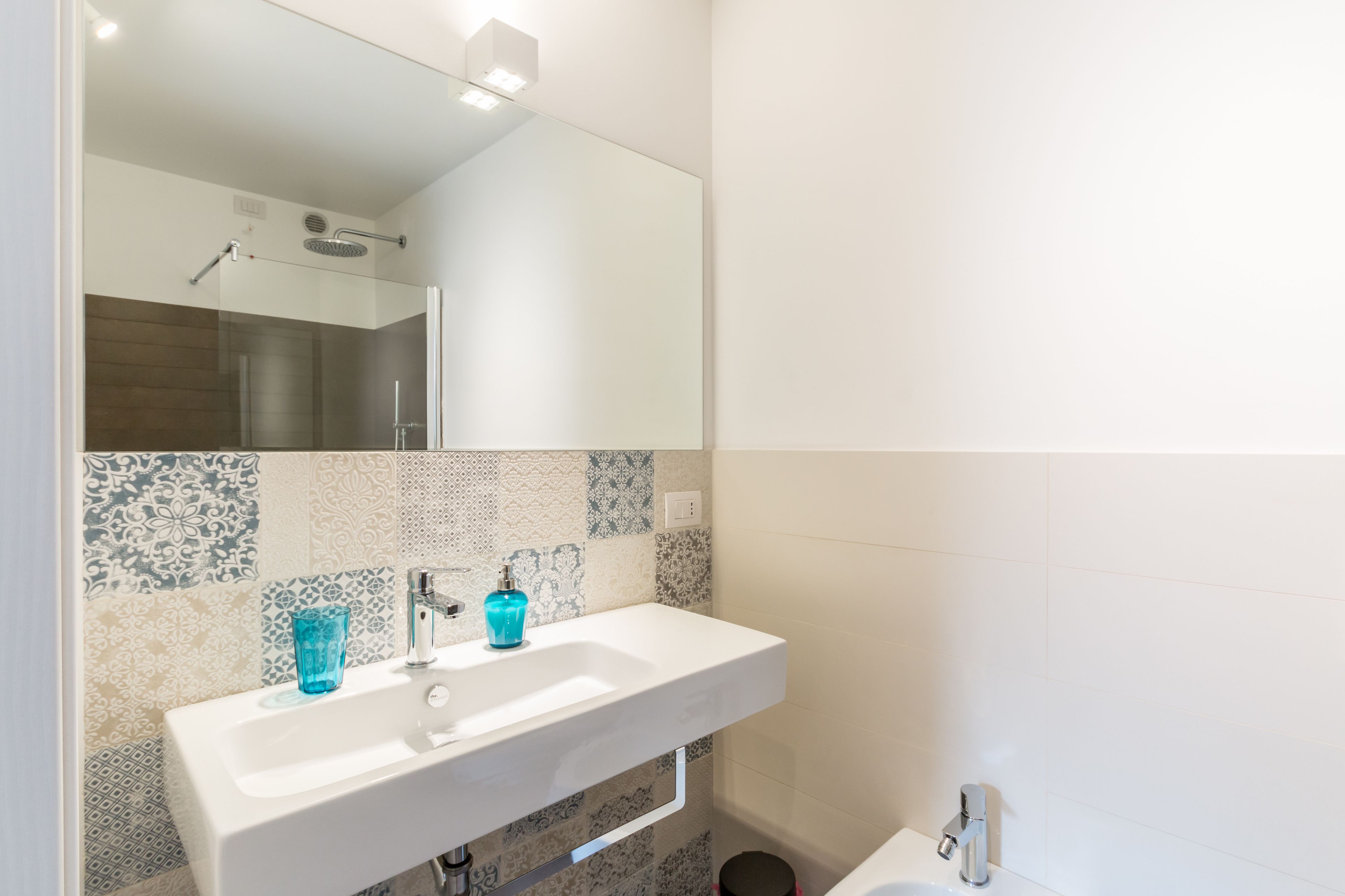 Ein Badezimmer mit einem weißen Waschbecken, einem blauen Glas und einer Dusche.