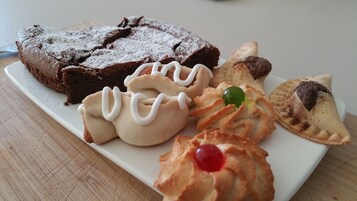 Un plato con varios pasteles, incluyendo un pastel de chocolate, profiteroles y una galleta cubierta de cerezas.