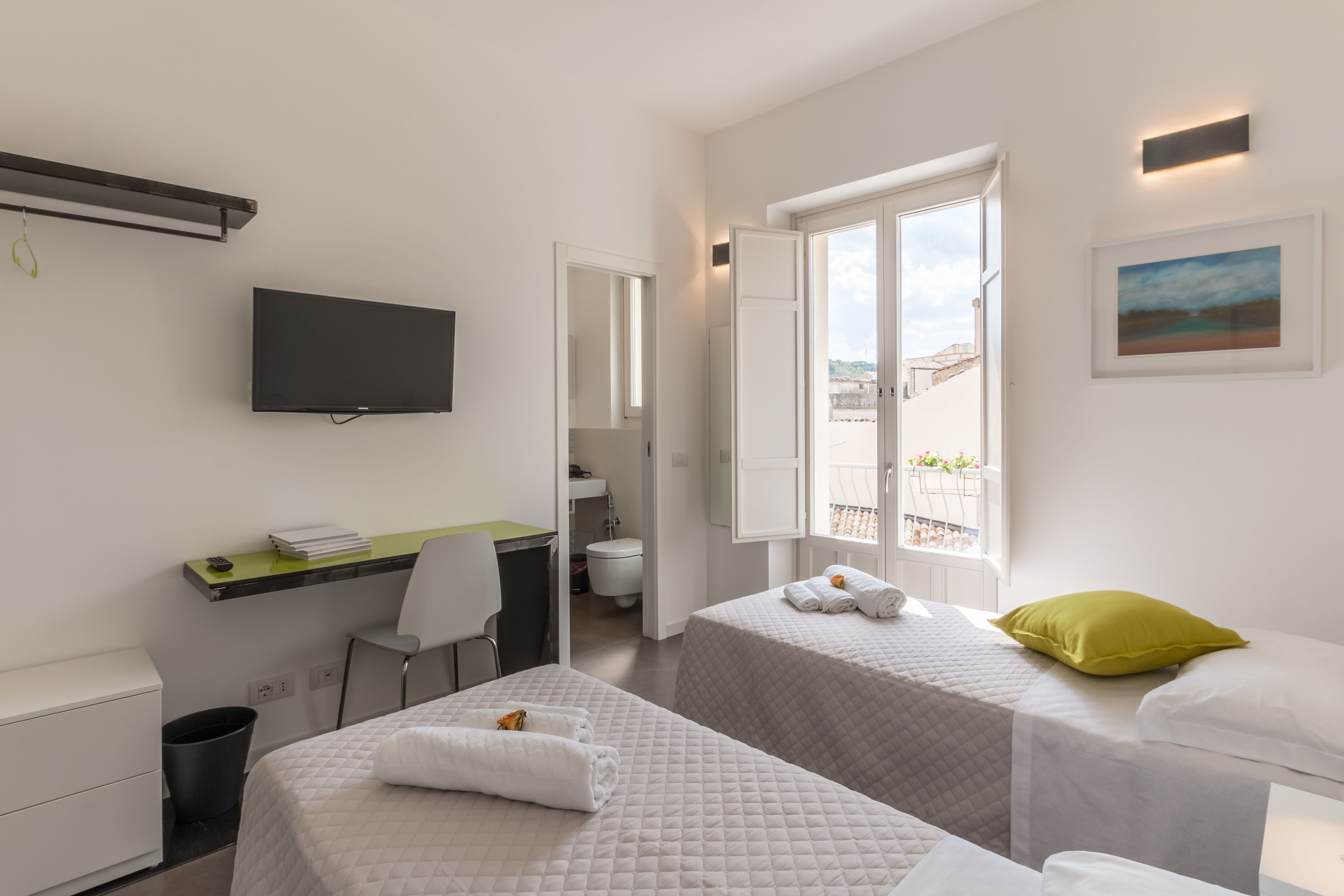 Une chambre d’hôtel avec deux lits, un bureau, une télévision et une fenêtre donnant sur un paysage agréable.