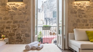 Un dormitorio con una cama grande, un sofá blanco y un balcón con vistas a edificios.