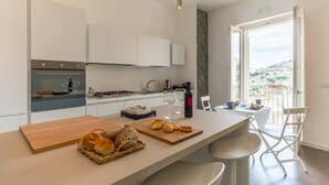 Una cocina moderna con una isla central, armarios blancos y vistas a un balcón.
