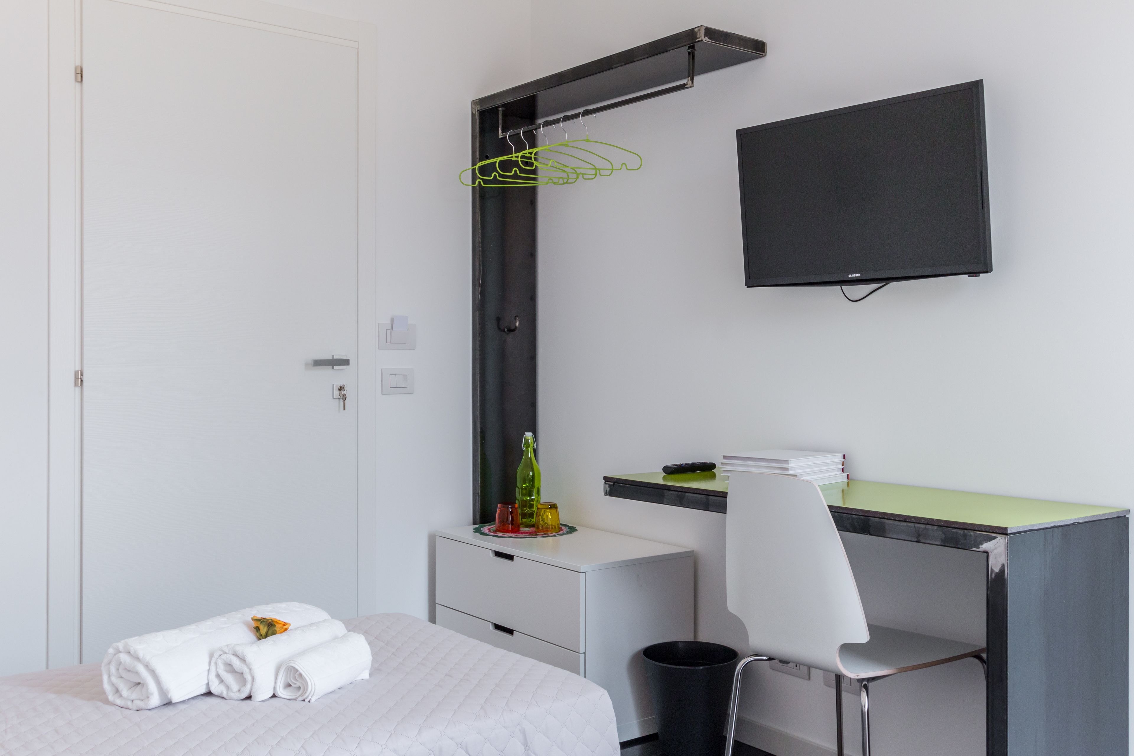 A hotel room with a bed, a desk, a chair, a TV, and a wardrobe.