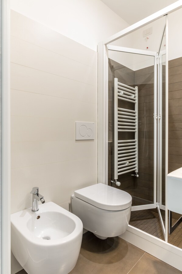 A modern bathroom with a bidet, toilet, and glass-enclosed shower. - Terrazza Dei Sogni - Terrace with a view (Ragusa)