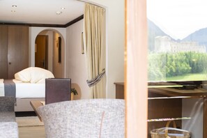 Une chambre d’hôtel équipée d’un lit, d’un bureau, d’une chaise, d’une télévision et offrant une vue sur une montagne.