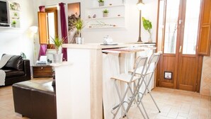 Um espaço de estar compacto com cozinha americana, sala de jantar com mesa e cadeiras, sofá e pequena mesa de centro.