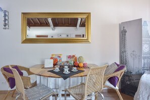 A dining area with wicker chairs, a round table, and a large mirror above. - Rome Holidays Resort (Rome)