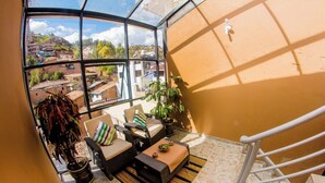 A balcony with wicker furniture, a potted plant, and a view of a residential area.