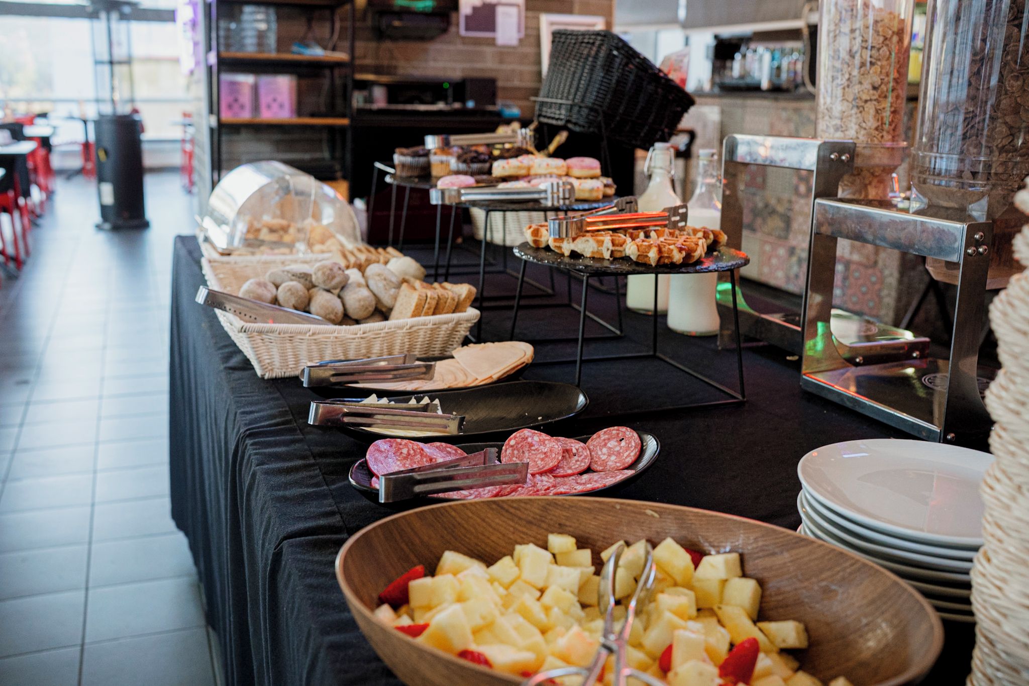 A buffet setup with various food items, including bread, pastries, and sliced meats.